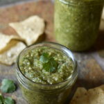 Close up of salsa verde with chips and cilantro garnish