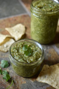 Close up of salsa verde with chips and cilantro garnish