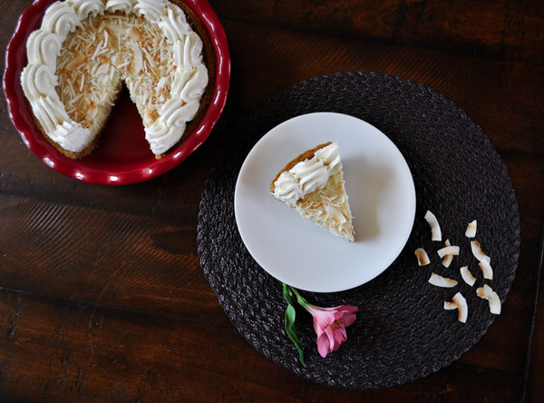 A slice of Coconut Cream Pie on a placemat then on a coffee table with a whole pie in the background