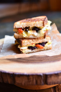 An Artichoke Olive Feta Sandwich on a decorative cutting board