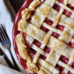 A Rhubarb Pie with a lattice crust and a backdrop of a napkin, fork, and knife