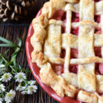 A Rhubarb Pie with a lattice crust and a backdrop of flowers, and pinecones