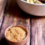 Pickled Mustard Seeds with a bowl of potato salad and dill garnish in the background