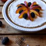 A whole blackberry peach cream cheese pie garnished with fruit, then two forks beside.