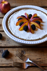 A whole blackberry peach cream cheese pie garnished with fruit, then two forks beside.