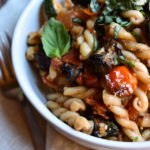 A bowl of Grilled Veggie Pasta on a napkin with a fork