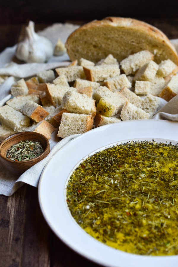 Garlic Herb Bread Oil Dip with sourdough bread in the background.