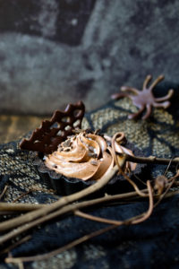 A chocolate mousse tart with a dark chocolate web garnish in and spider one in the background.
