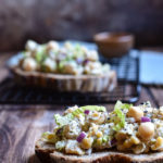 An open-faced chickpea tuna sandwich with one in the background