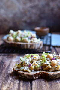 An open-faced chickpea tuna sandwich with one in the background