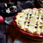 Brandy Apple Pie with apples, a ball of twine, and an old fashioned candlestick in the background.