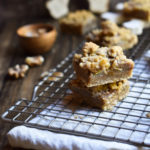 Spiced Pear Crumb Bars on a cookie rack with more and a big wooden snowflake, and walnuts in the background