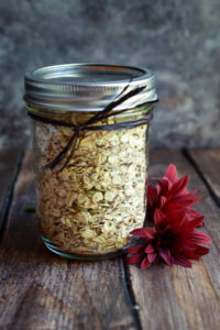 A mason jar of oats, seeds, and spices with flowers beside