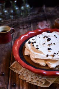 Coffee Cream Pie with a red cup of espresso, beans, branches, leaves, and vases in the background