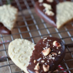 An Embossed Heart Chocolate Dipped Sugar Cookie on a wire rack with others in the background