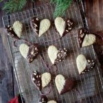 An Embossed Chocolate Dipped Sugar Cookie on a wire rack with others and a green branch in the background