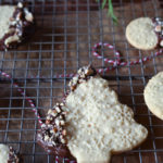 An Embossed Tree Chocolate Dipped Sugar Cookie on a wire rack with other moon shaped in the background