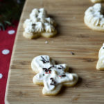 A gingerbread man frosted sugar cookie on a cutting board with others in the background