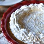 Creamy Cheesecake Pie with Peanut Butter, Honey & Coconut in a decorative napkin with a plate with utensils in the background.