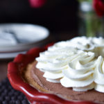 A Double Chocolate Truffle Pie topped with forks, plates and red and white and pink tulips in the background