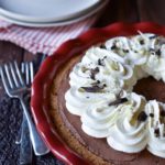 A Double Chocolate Truffle Pie topped with dark and white chocolate shavings and forks, plates and red and white striped napkins in the background