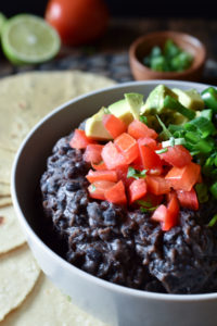 A bowl of Smashed Black Beans made in the Instant Pot with tortillas surrounding
