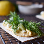 Hummus Dill Snack Crackers on a wire rack with others and a lemon in the background