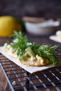 Hummus Dill Snack Crackers on a wire rack with others and a lemon in the background
