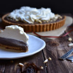 A slice of Spiced Almond Chocolate Tart with the rest in the background.