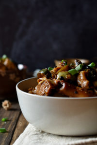 A bowl of Sue's Vegetable Chow Fun with a small bowl and cup of tea in the background.