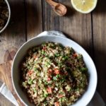 Lemon Vegetable Quinoa Salad with a wood serving spoon and lemon in the background.