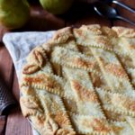 Perfect Spice Pear Pie with pears and silverware in the background