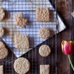 A wire rack of Flower Embossed Lemon Sugar Cookies with a tulip in the background