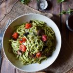 An overview of Homemade Pesto Over Noodles & Farro with a glass of wine and dish of salt and pepper in the background.