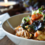 Instant Pot Lentil Quinoa Cabbage Stew with a napkin, kale, and lit candle in the background.