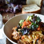 Instant Pot Lentil Quinoa Cabbage Stew with a napkin, kale, cut bread, and scattered green lentils in the background.