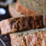 Cut and scattered pieces of 100% Whole Grain Zucchini Bread on a baking rack.