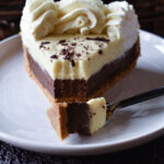 A slice of Orange Chocolate Cream Pie with a bite on a fork and spring flowers in the background.