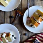 Two slices of Berry Almond Cake plated with forks and an American flag in the background.