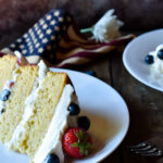 Two slices of Berry Almond Cake plated with forks and an American flag in the background.