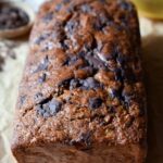 A close up and overview of Chopped Chocolate Banana Bread with a small bowl of chopped chocolate and bananas in the background.