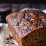 Chopped Chocolate Banana Bread with a chunk of chocolate in the back and slivers to the side.