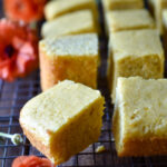Pieces of Orange Spiced Cornbread and orange flowers to the side.