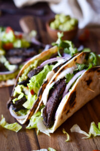 Two folded Roasted Portobello Mushroom Tacos and one unfolded in the background.