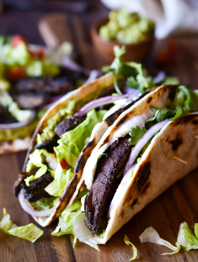 Two folded Roasted Portobello Mushroom Tacos and one unfolded in the background.