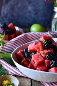A close up of Watermelon Blackberry Summer Salad with a small plate full and a lime in the background.