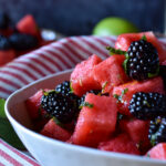 A close up of Watermelon Blackberry Summer Salad with a small plate full and a lime in the background.
